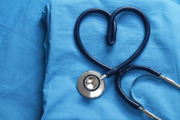 Close-up of blue nurse's scrubs with a stethoscope curled into a heart shape