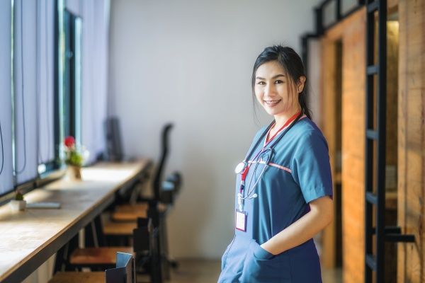 Side view of a female Asian American Nurse smiling with her hands in the pockets of her scrubs
