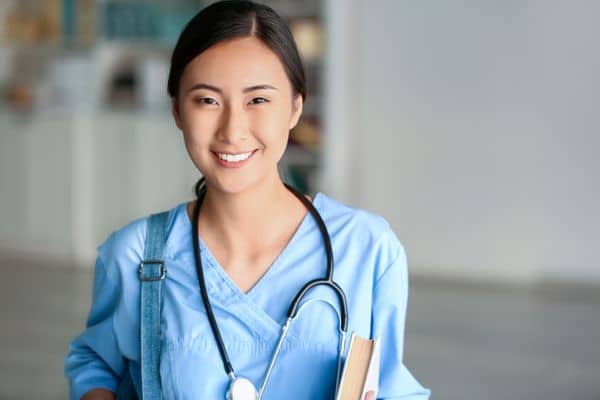 Smiling Asian American female nurse in blue scrubs