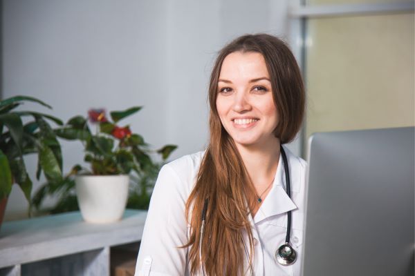 Smiling female family nurse practitioner sitting in front of a computer monitor