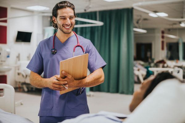 Smiling male nurse with clipboard checking in on his patient