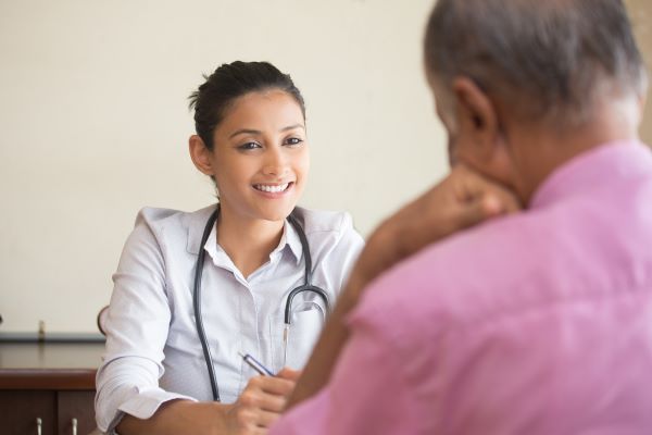 Young female family nurse practitioner talking to an older male patient