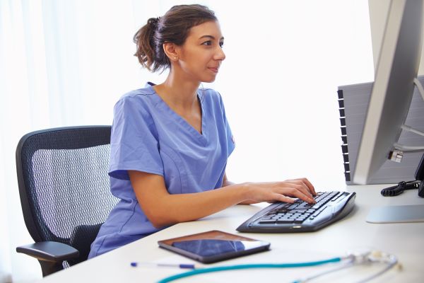 Nurse in purple scrubs participating in a telehealth appointment on her computer
