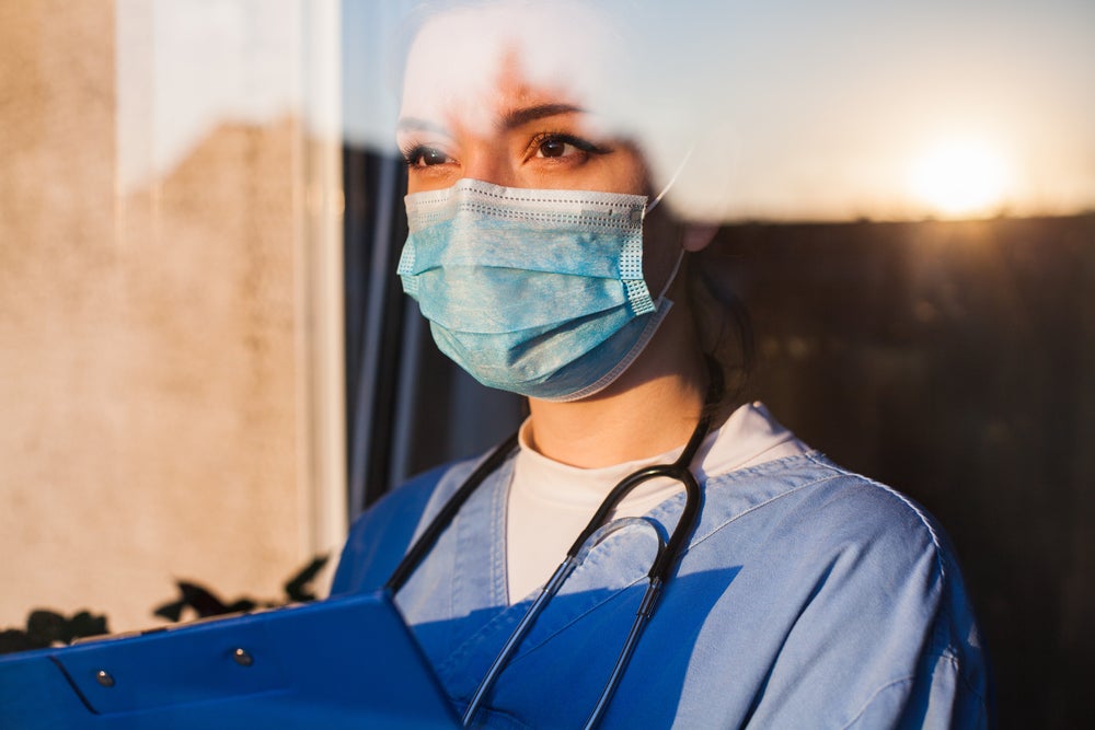 A nurse looking wistfully out of a window