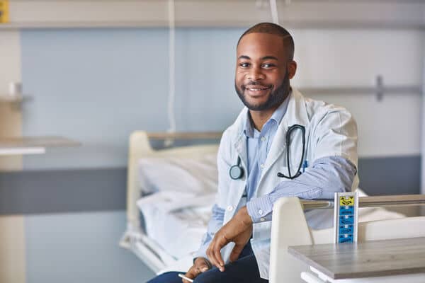 Confident male nurse practitioner sitting in hospital room
