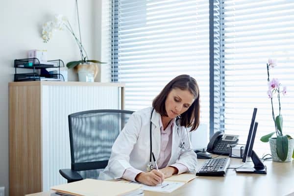 Female nurse practitioner taking notes at her office desk
