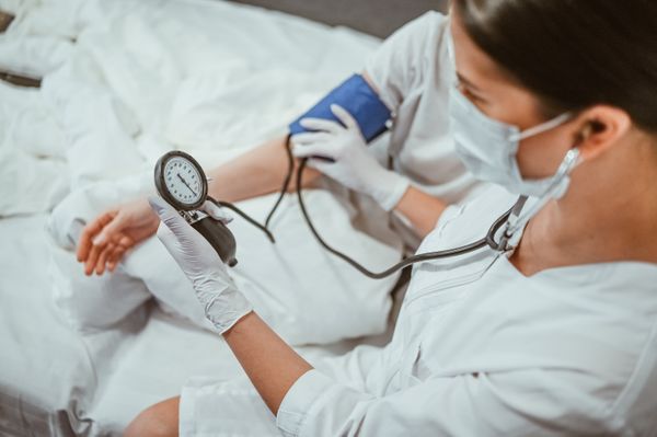 masked nurse checking vitals