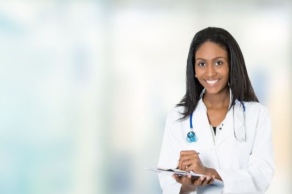 Smiling nurse practitioner in a white lab coat holding a clipboard