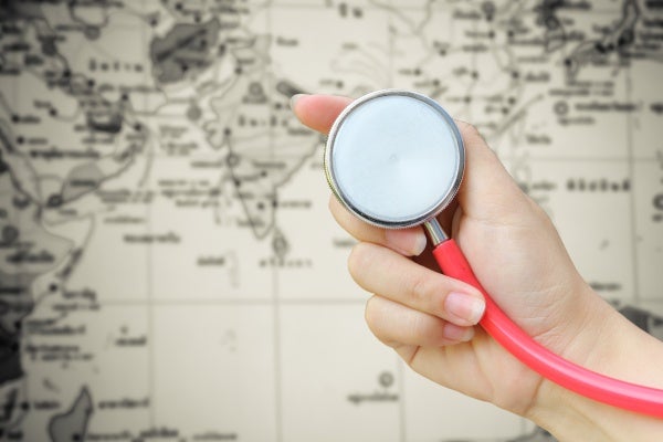 Female's hand holding a stethoscope over a map of the world