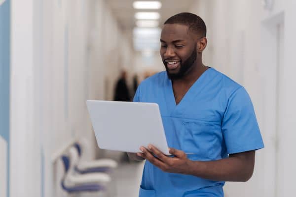 African American male nurse wearing blue scrubs in hospital setting
