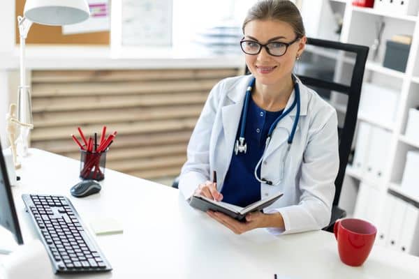 Smiling female nurse practitioner with notebook in bright office setting