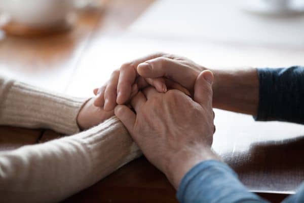 Younger hands clasping older hands