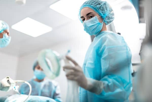 Female nurse wearing face mask and surgical gear in operating room