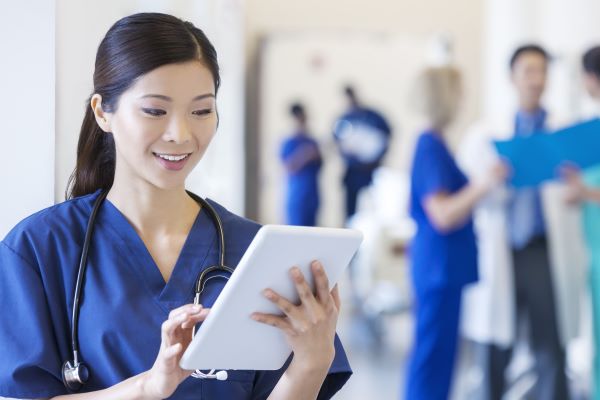 Asian American female nurse using a tablet device on the job