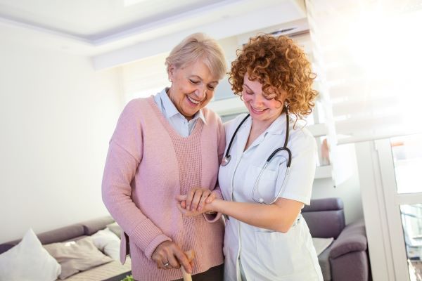 A nurse practitioner helping an elderly female patient walk