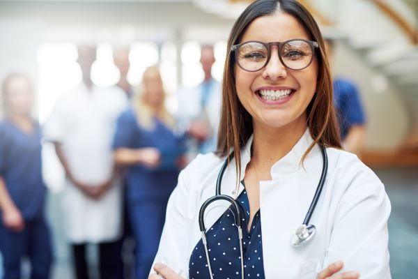 Smiling female nurse practitioner wearing glasses and a white lab coat