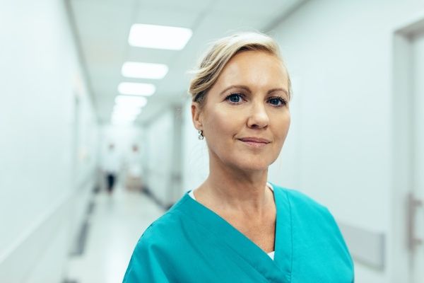 Registered nurse in green scrubs standing in a hospital corridor
