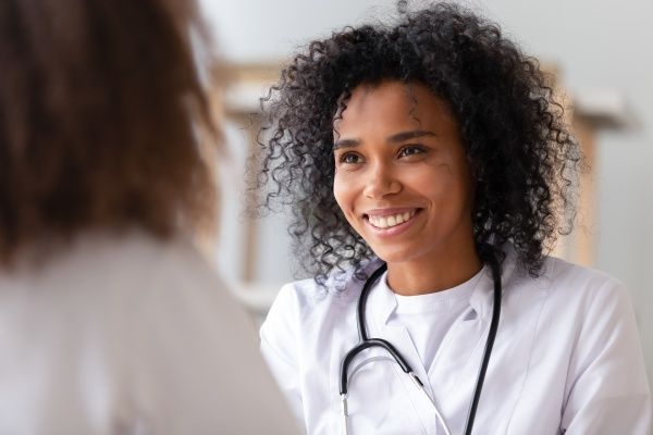 Smiling nurse practitioner in a white coat talking to her patient