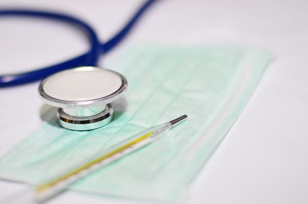 Close-up of a hospital mask, needle, and stethoscope