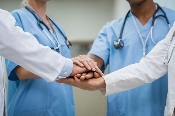 A group of nurses and doctors placing their hands together in a circle