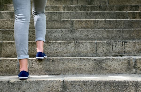 Close-up of a woman's legs walking up stone steps