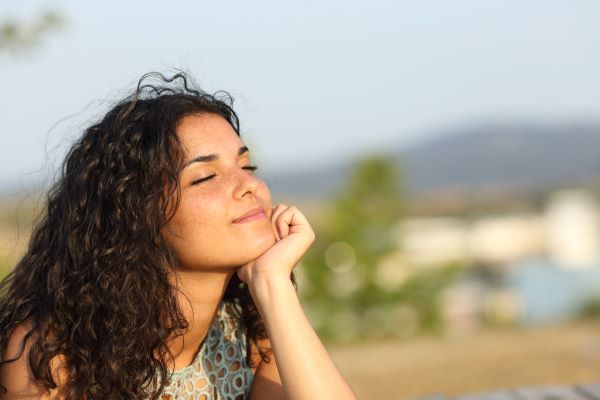 Serene woman resting her head on her hand with eyes closed in outdoor setting