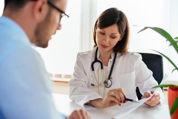 Young female family nurse practitioner reviewing health records with her adult male patient