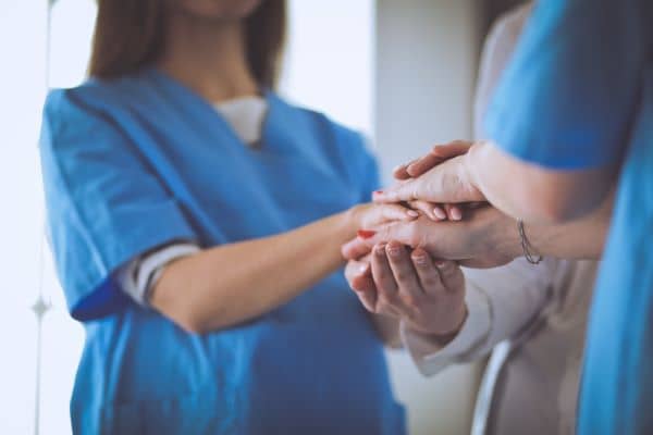 Nurses in blue scrubs clasping hands